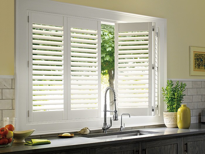 Hunter Douglas Palm Beach Shutters in white overlooking the sink in the yellow wall kitchen.
